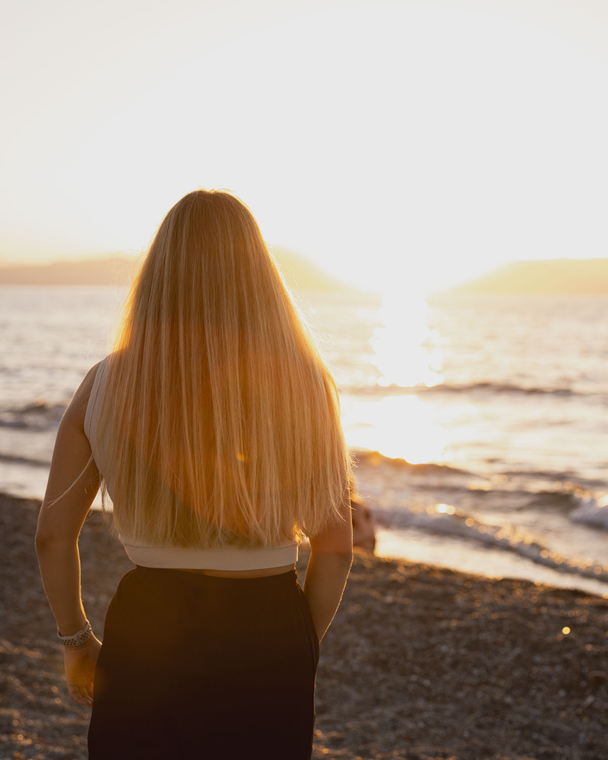 Frau genießt Sonnenuntergang am Strand mit Meer