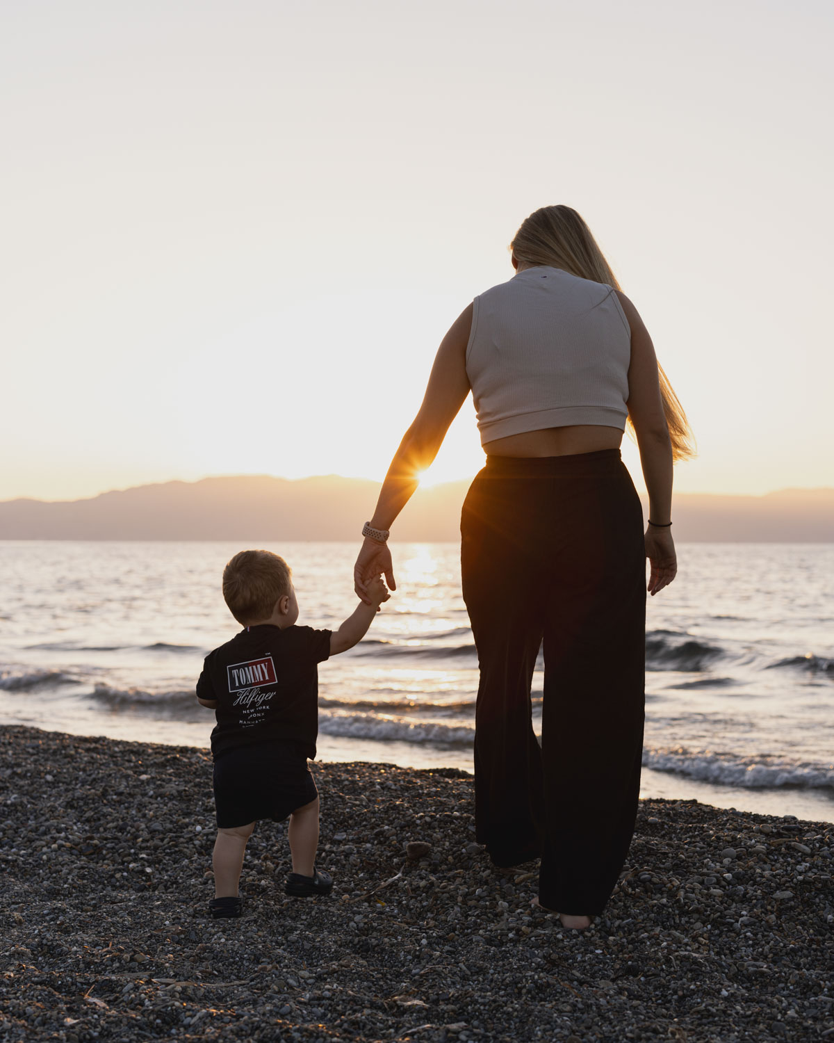 Frau und Kind spazieren am Strand entlang